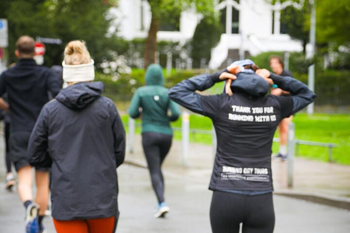 hópur fólks að ganga eftir gangstétt í rigningunni