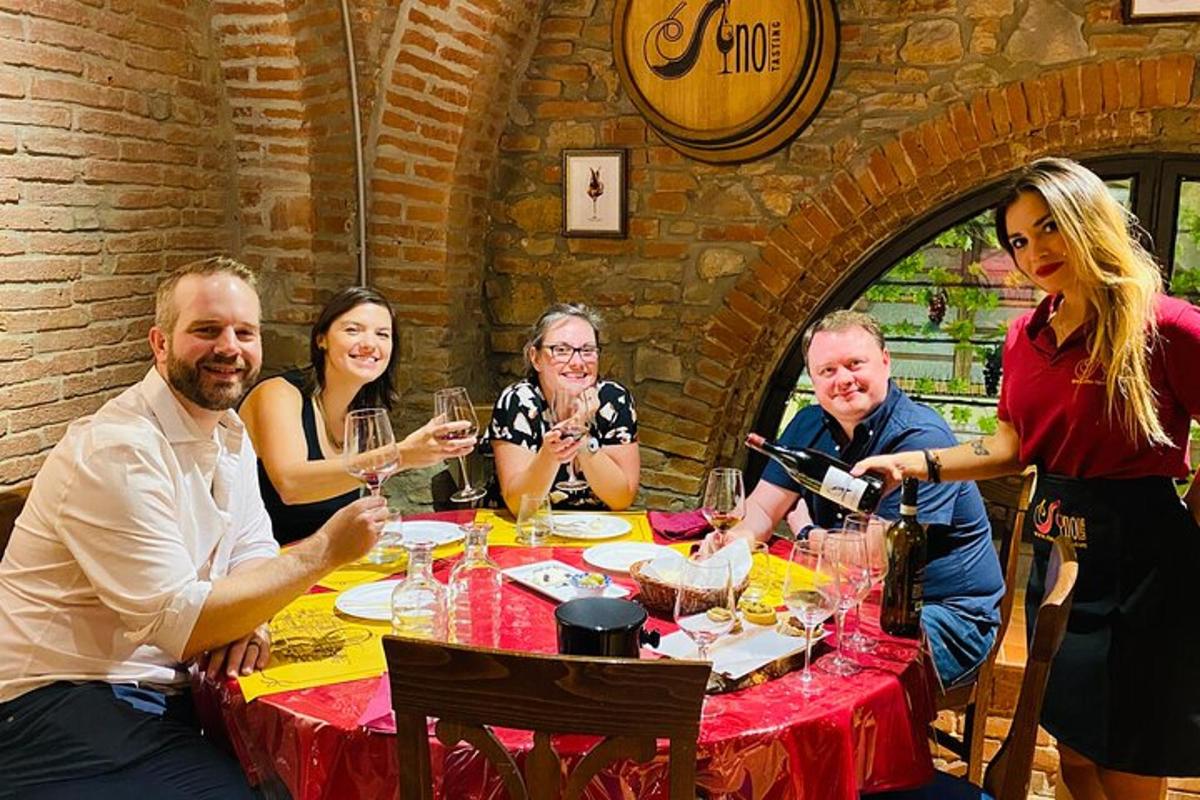 skupina lidí sedících kolem stolu s vinnými sklenicemi