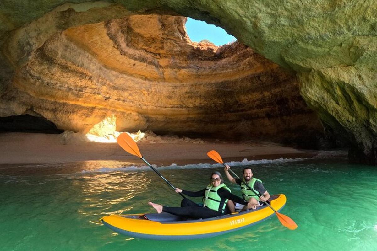 two people in a kayak in front of a cave