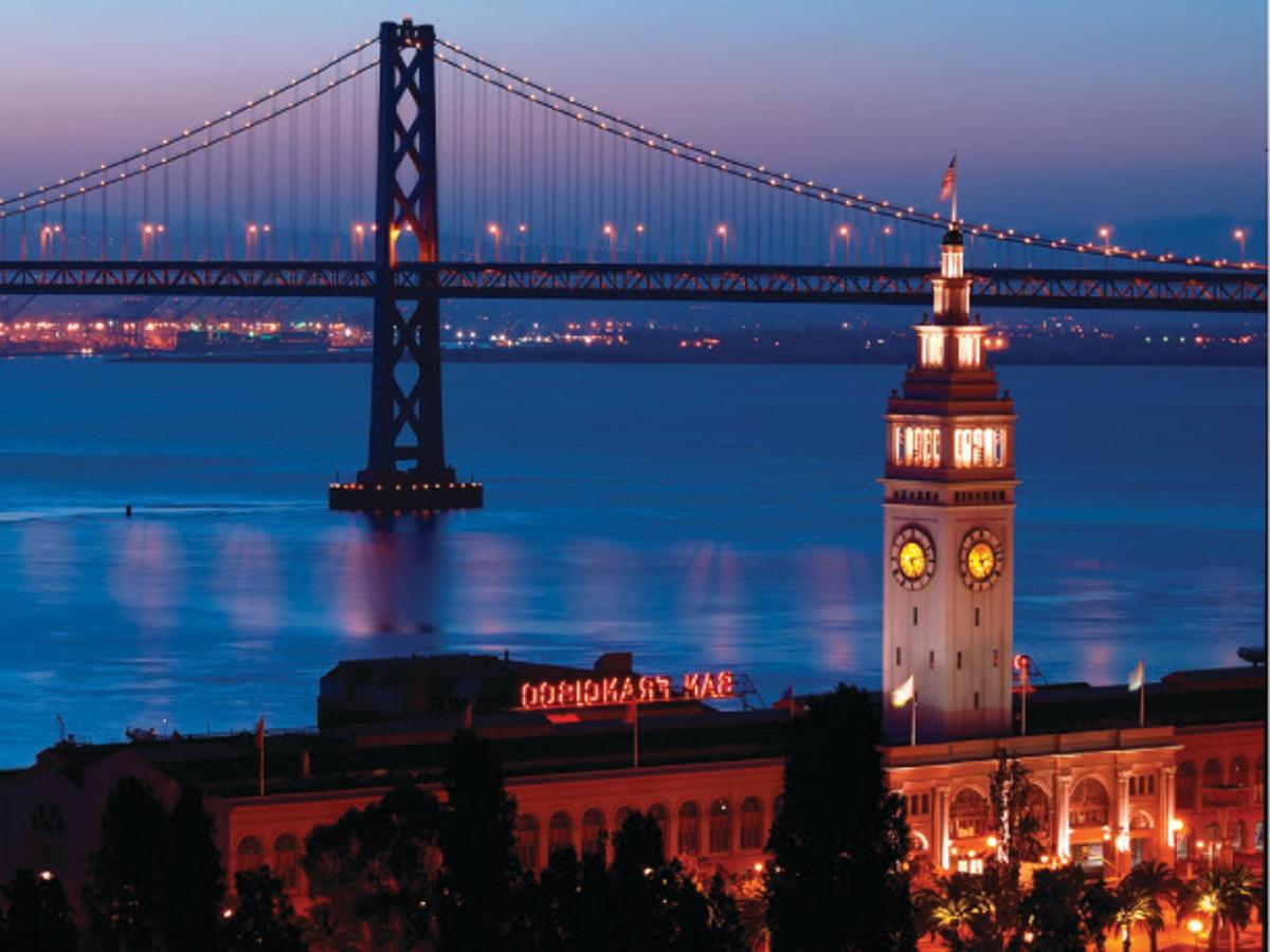 a tall clock tower with a bridge in the background