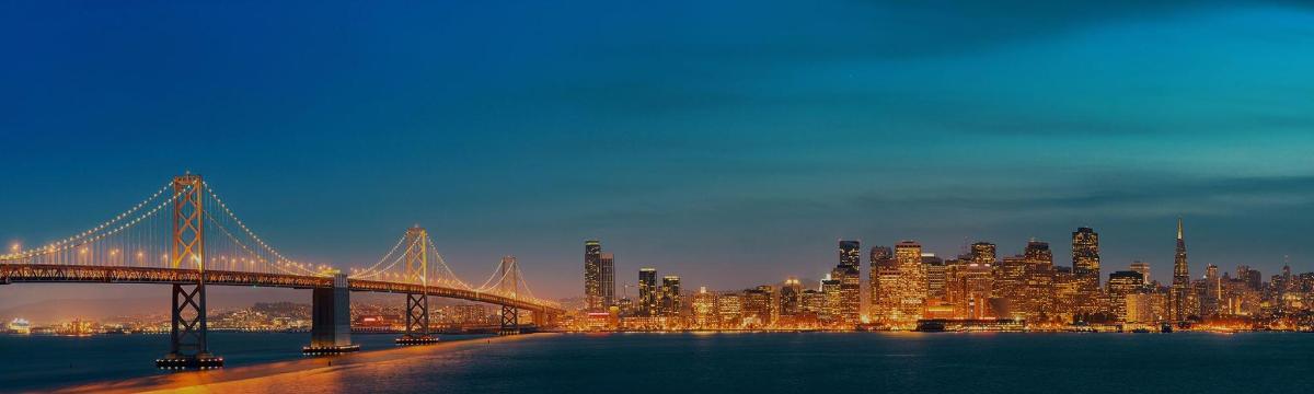 a bridge over the water with a city at night