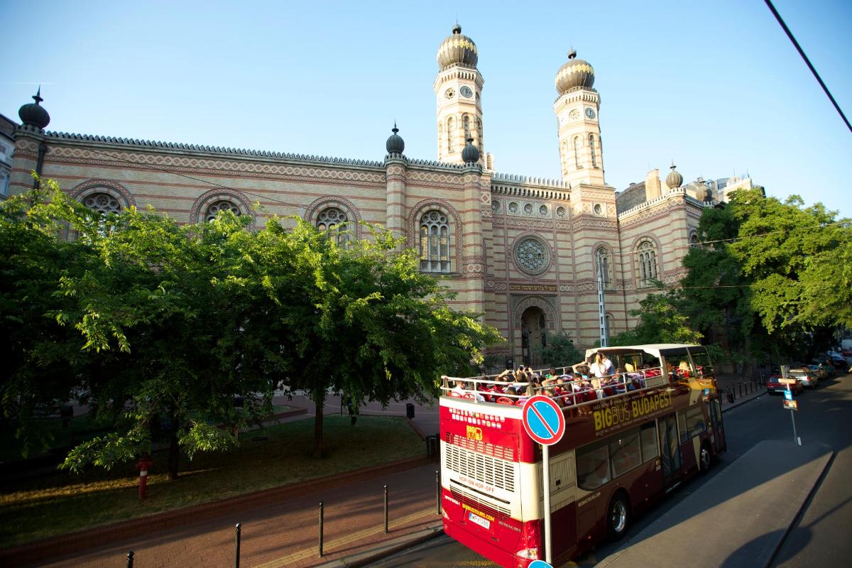 červený dvoupatrový autobus projíždějící kolem budovy