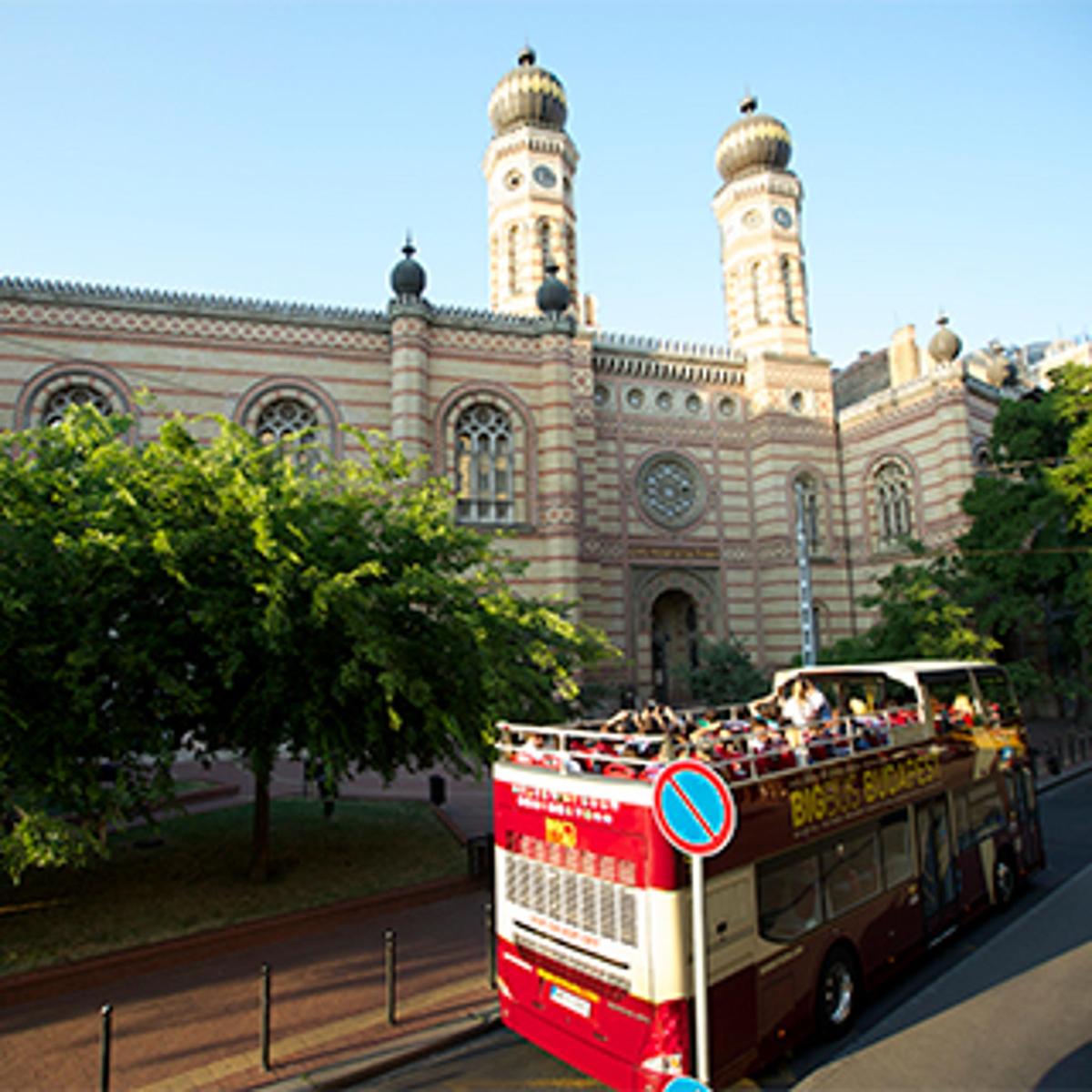 červený dvoupatrový autobus projíždějící kolem budovy
