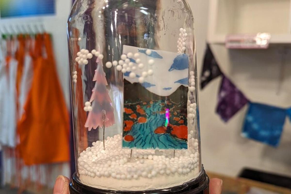 a person holding a glass bottle with a picture of a forest