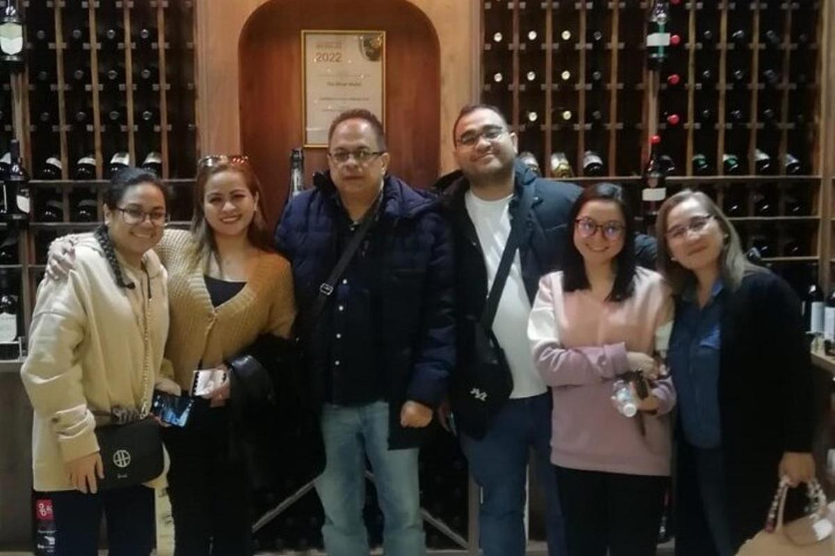sekumpulan orang berdiri di hadapan botol wain