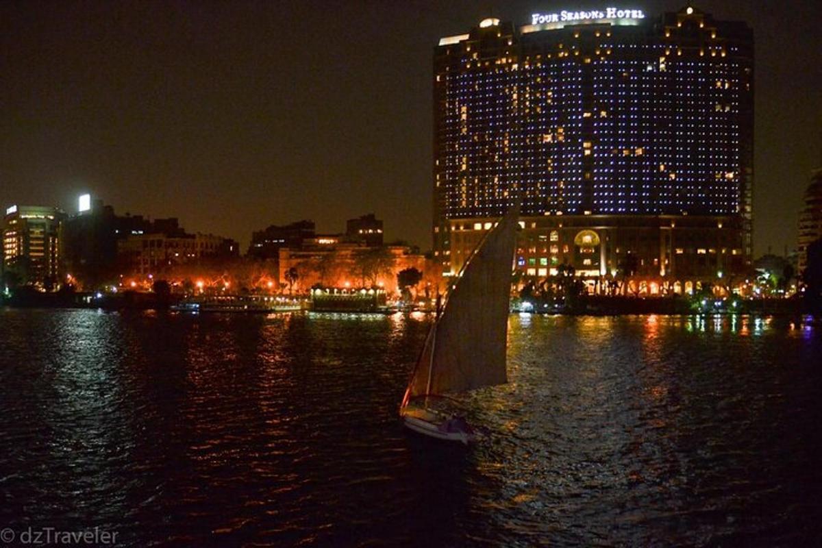 a sailboat in the water with a city at night