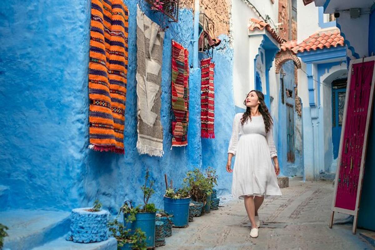 a woman walking down a street in front of a blue wall