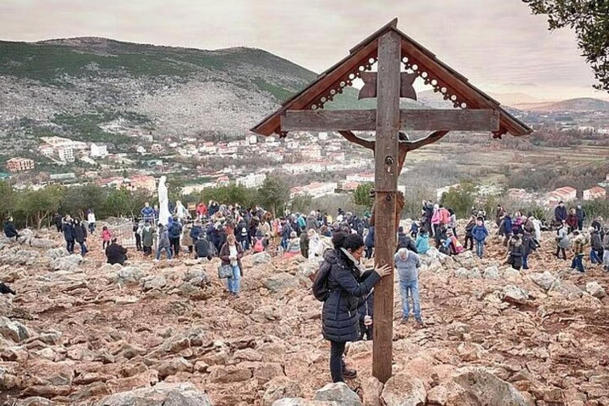 Una multitud de personas de pie alrededor de un cartel de madera.