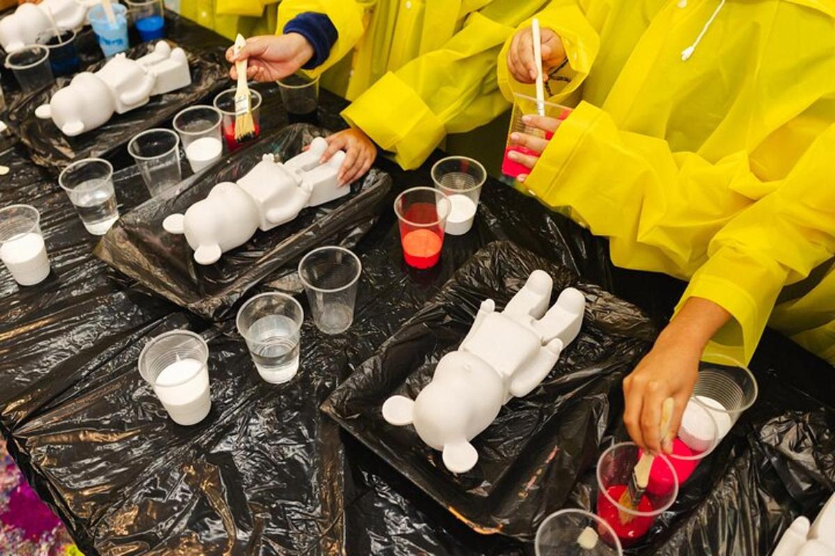 um grupo de pessoas fazendo potes brancos em uma mesa