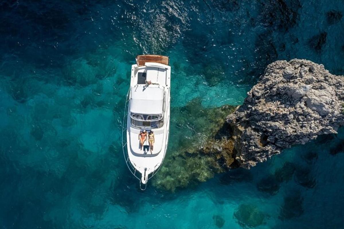 um barco branco na água ao lado de uma rocha