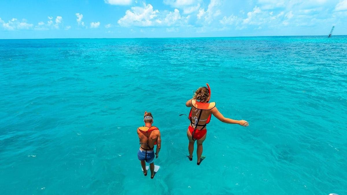 dos personas caminando en el agua en el océano