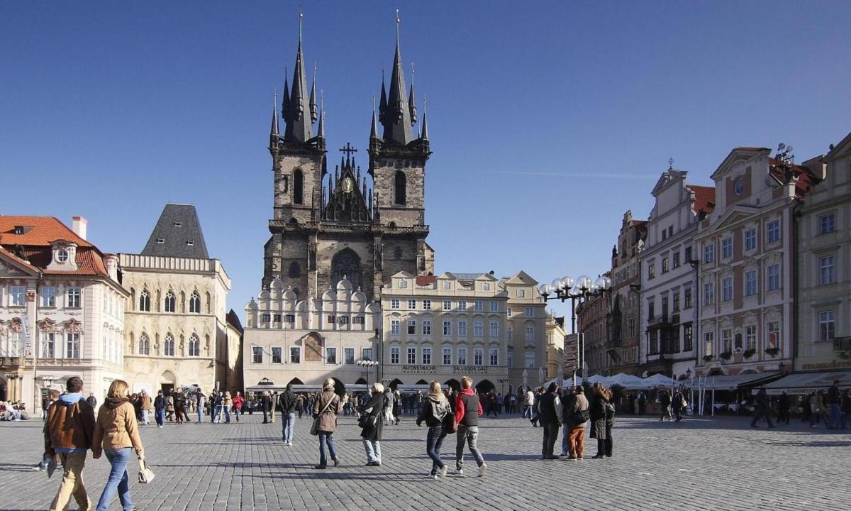 a group of people walking in a city square with a church