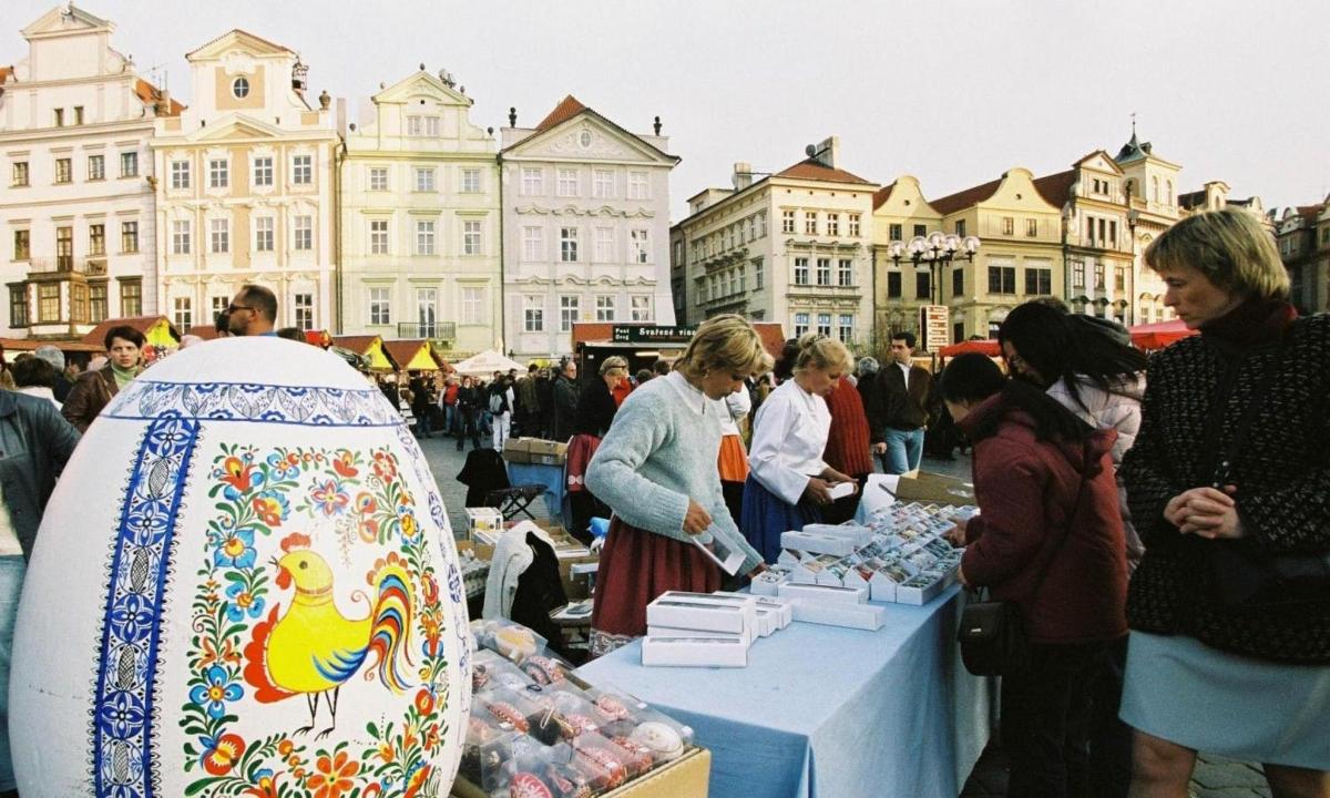 a group of people standing around a market with a vase