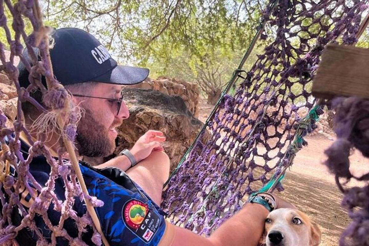 muž sedící v houpací síti se psem