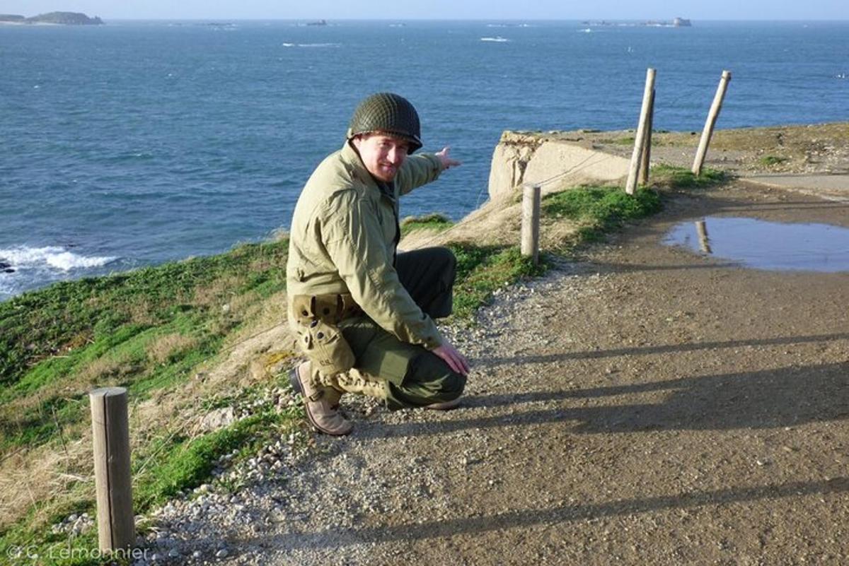 a man kneeling on the side of a road next to the ocean