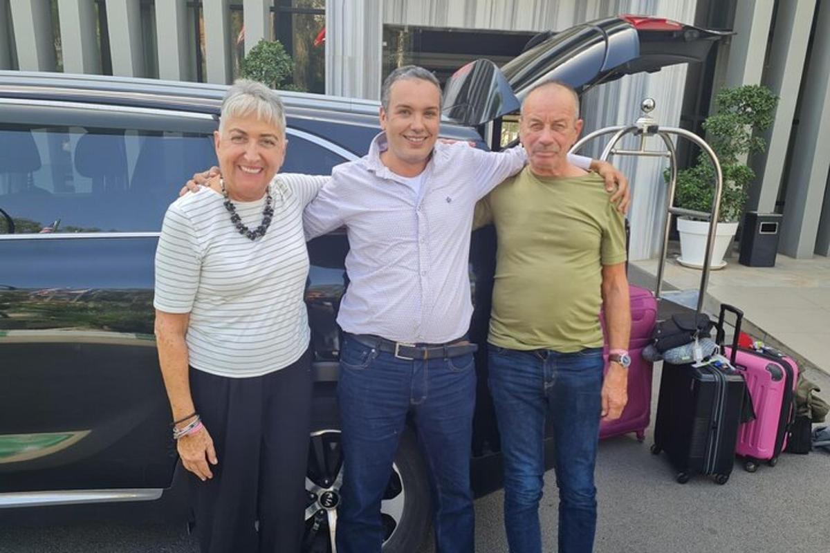 two men and a woman standing in front of a car