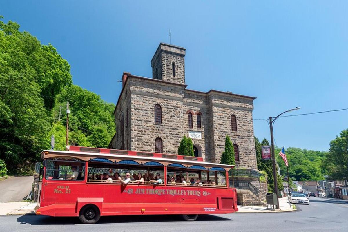 a red trolley driving down a street in front of a building
