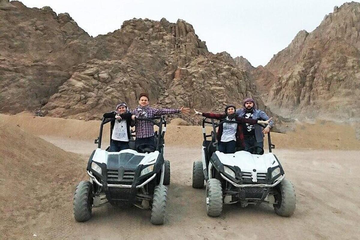 un gruppo di persone in piedi su veicoli a quattro ruote nel deserto