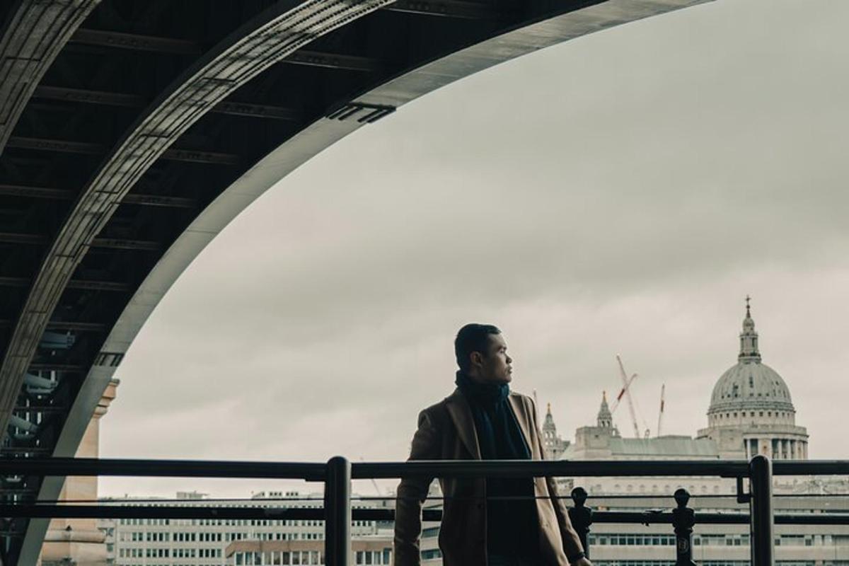 um homem caminhando sob uma ponte em frente a um prédio