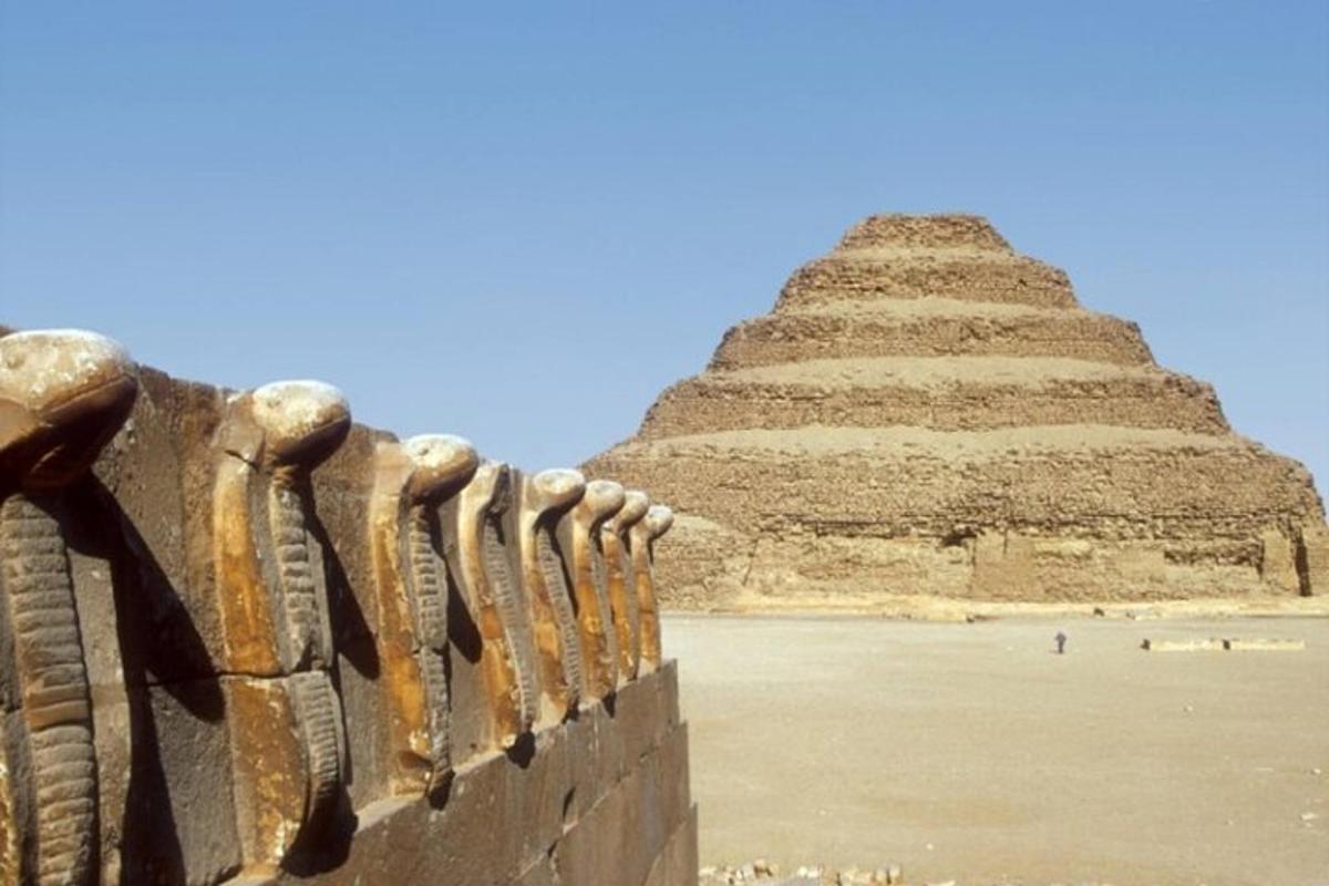 una piramide dietro un muro con una recinzione di fronte