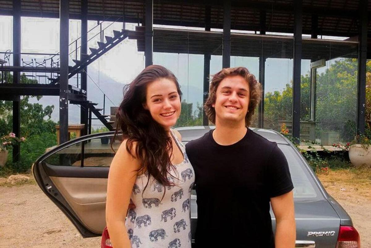 a man and a woman standing in front of a car