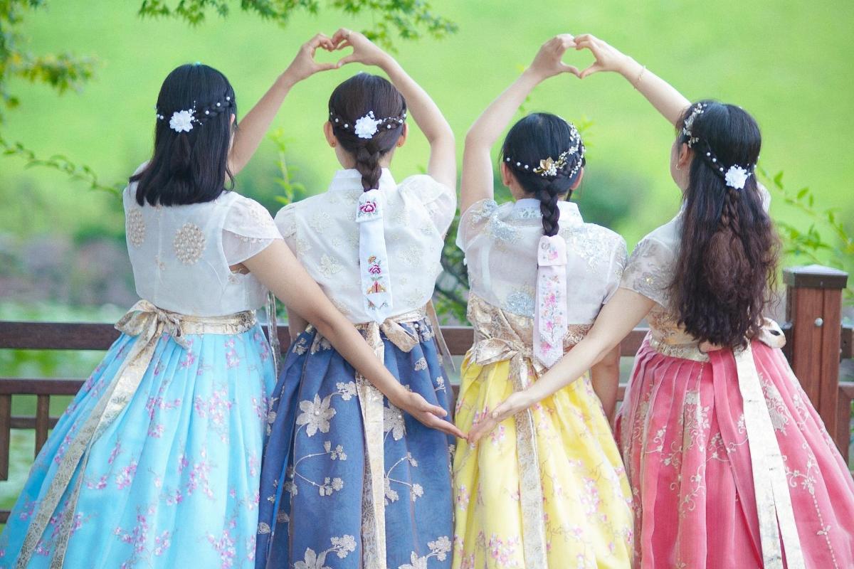 ドレスを着た4人の女の子がハートの形を作っている