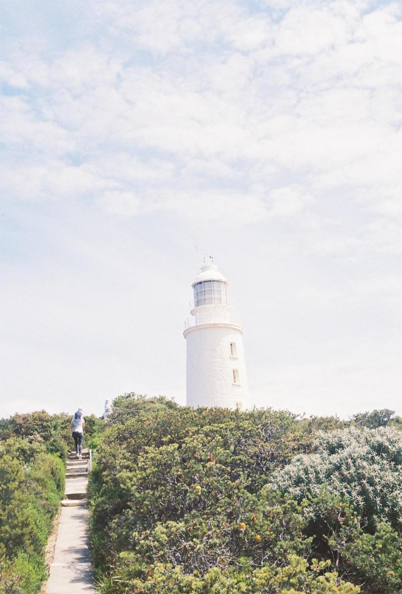 um homem subindo as escadas em direção a um farol