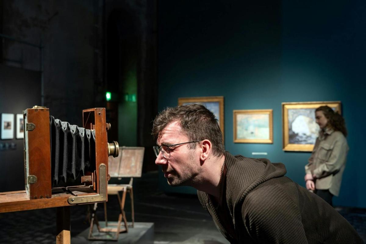 a man sitting in front of an object in a museum