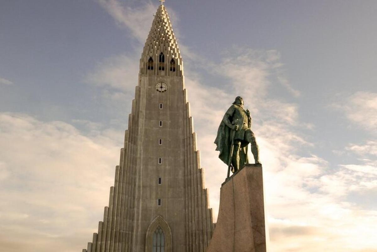 una estatua frente a un edificio con una torre de reloj