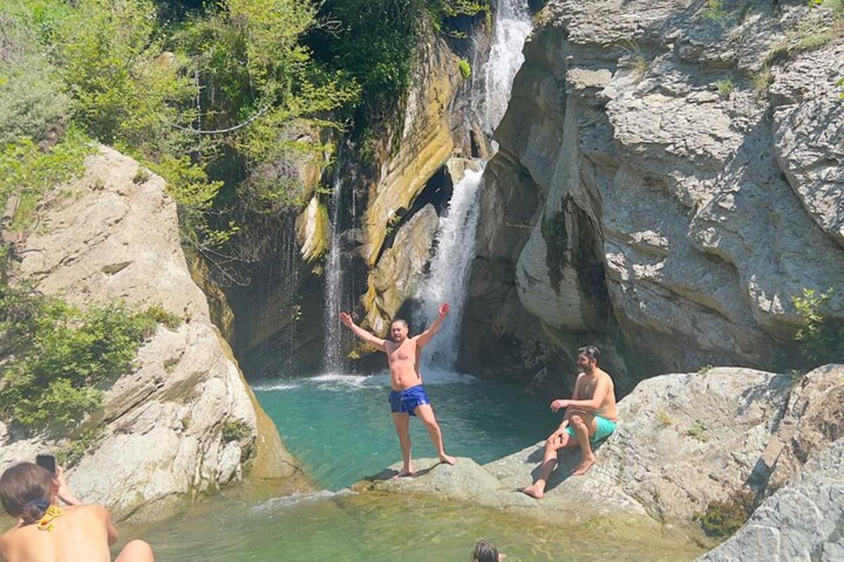 um grupo de pessoas na água perto de uma cachoeira
