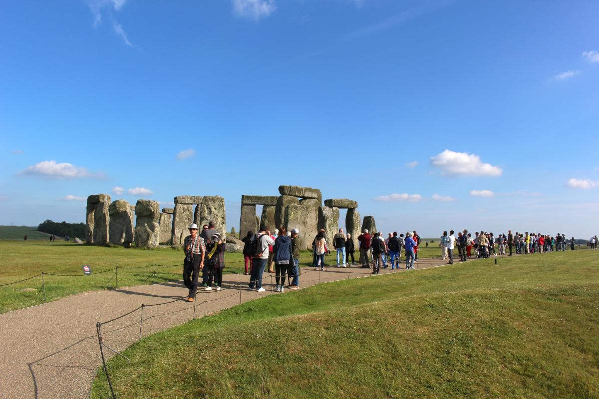 Velká skupina lidí procházejících se kolem Stonehenge