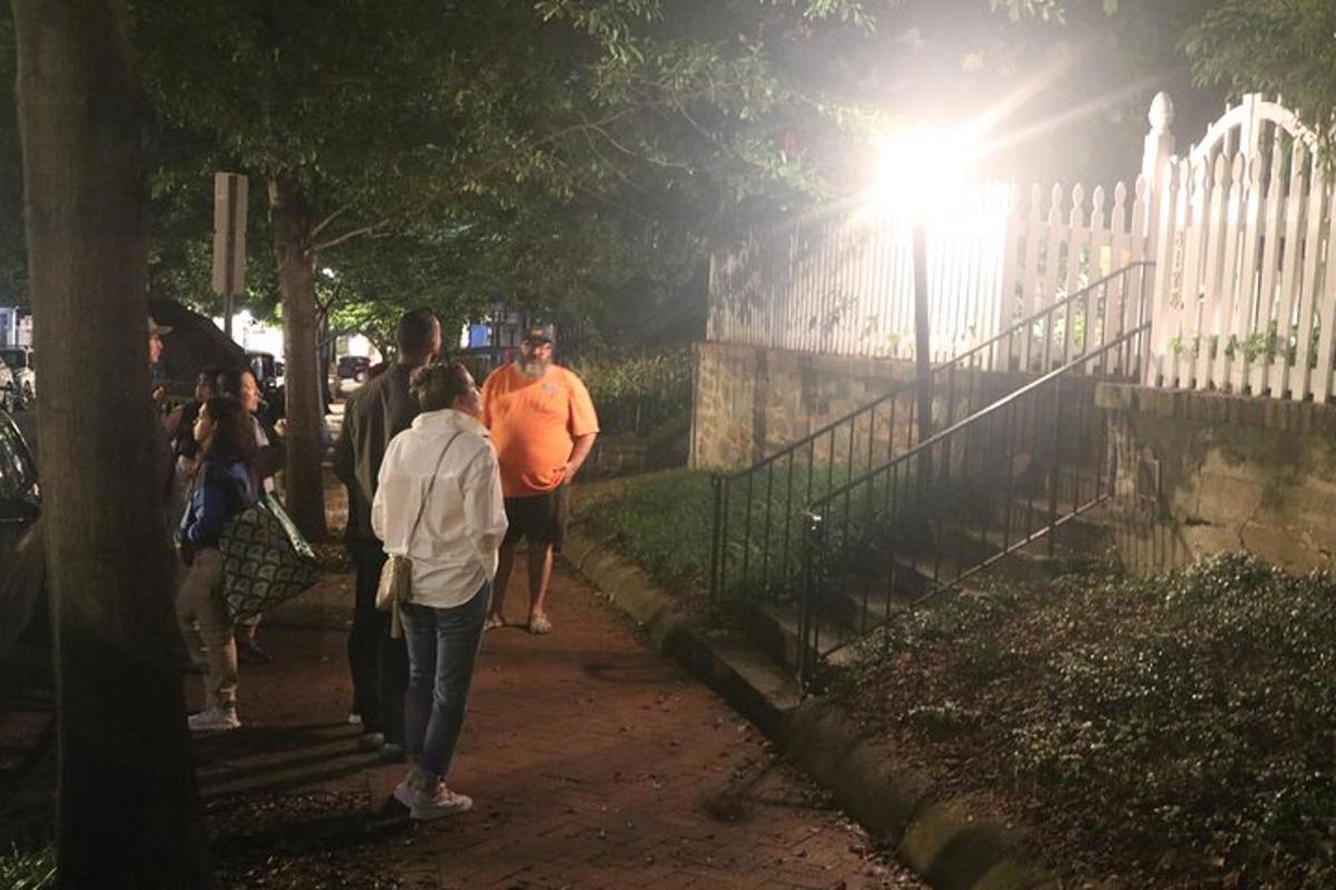 a group of people walking down a sidewalk at night