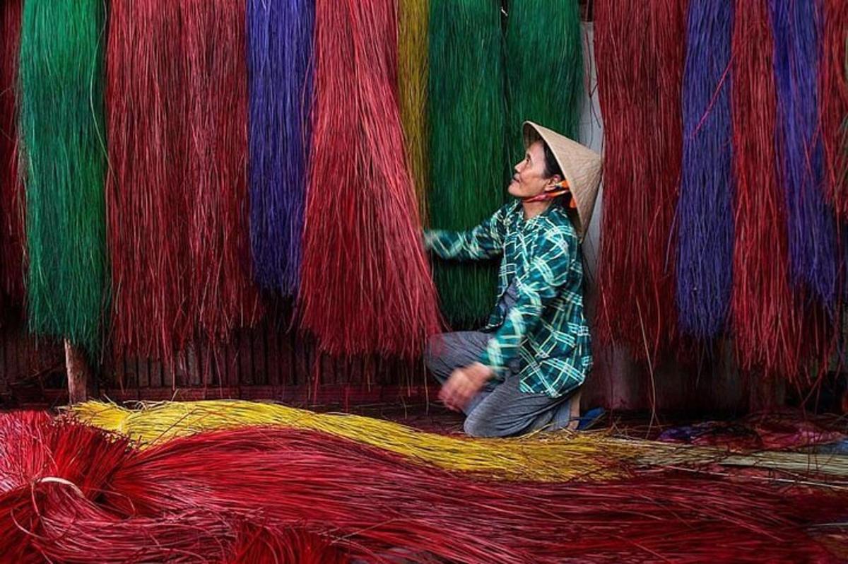 una persona asseguda davant d'una paret de fil de colors