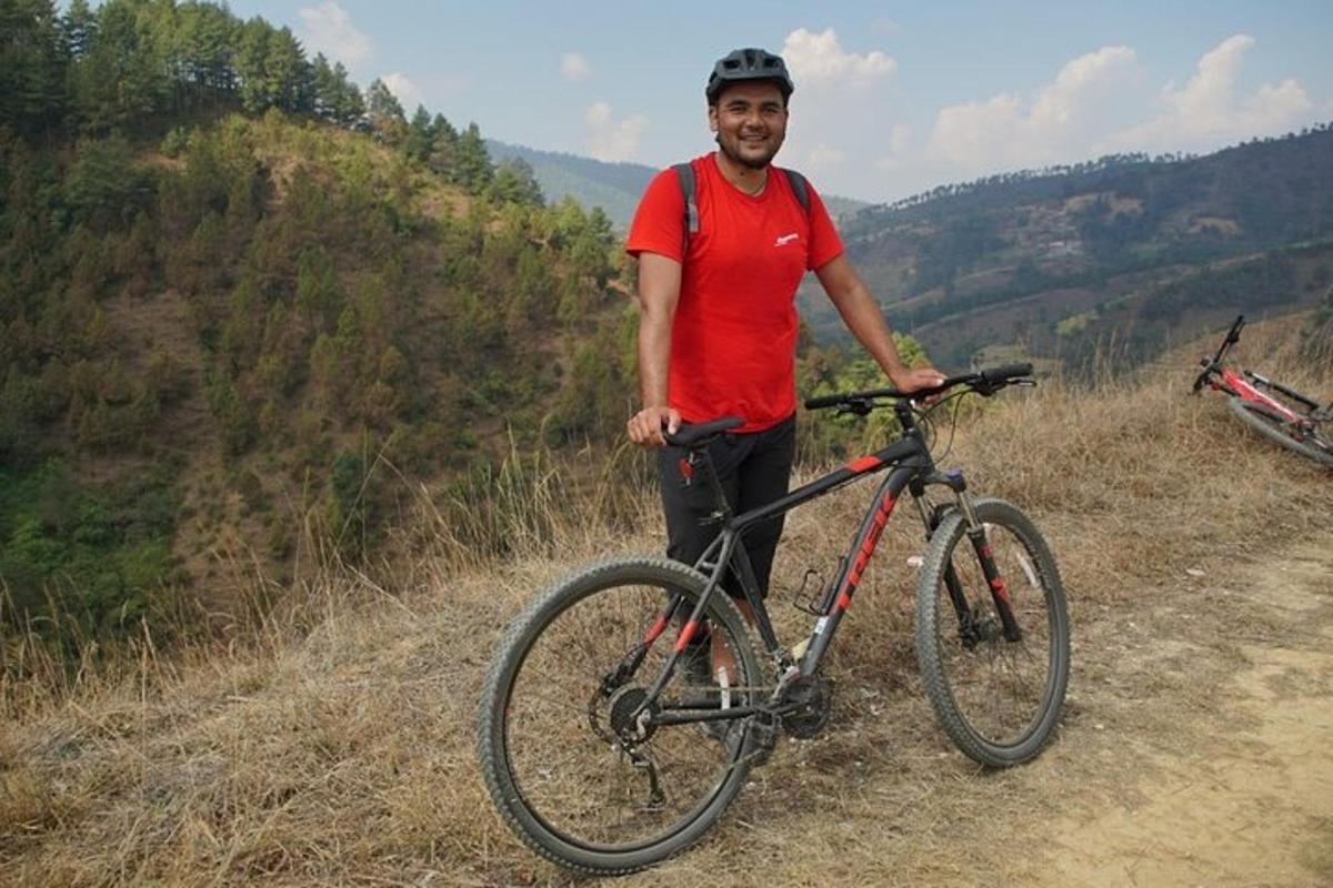 um homem parado ao lado de uma bicicleta em uma colina