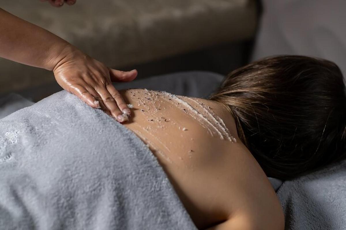 a woman laying on a bed with sand on her back