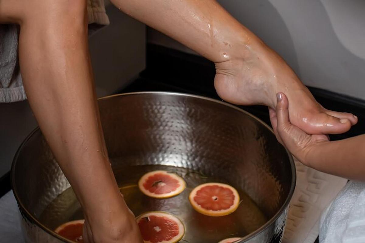 a person with their feet in a bowl with grapefruit