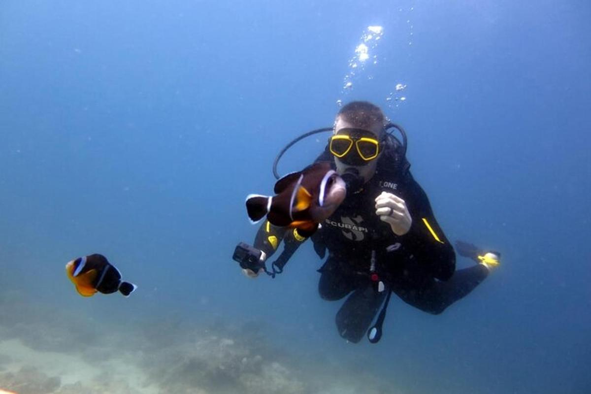 una persona in muta da sub con una macchina fotografica in acqua