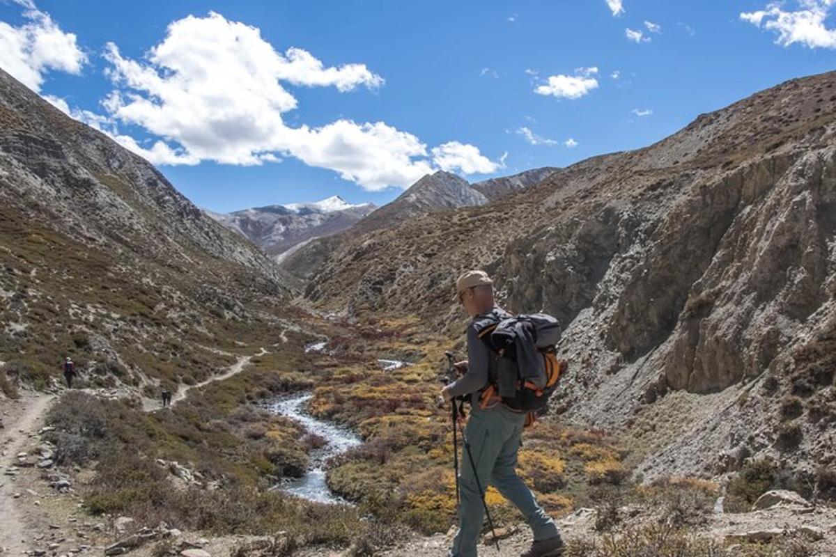 a man with a backpack walking through a mountain valley