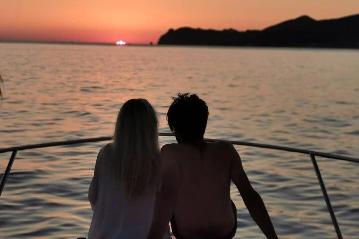una parella asseguda en un vaixell mirant la posta de sol