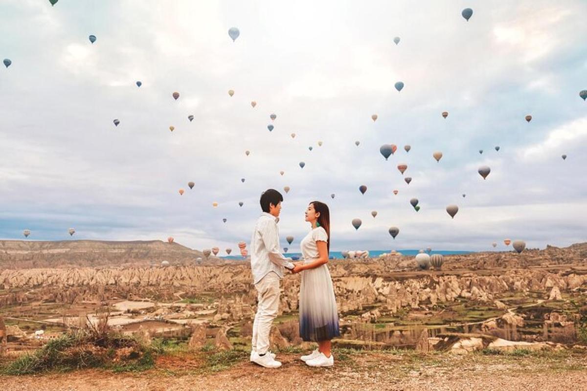sepasang suami isteri berdiri di hadapan padang dengan belon