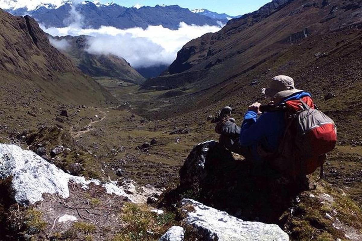 Un hombre sentado en la cima de una montaña mirando un valle.