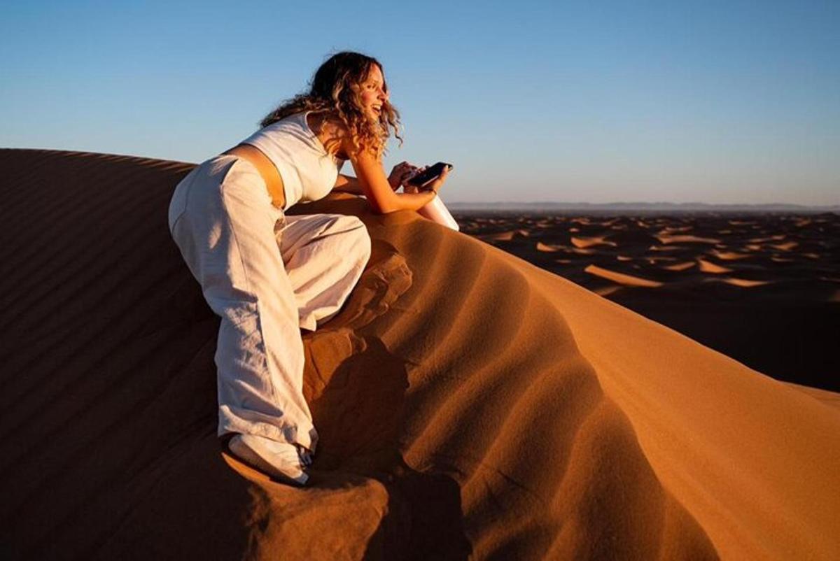 a woman sitting on a sand dune in the desert