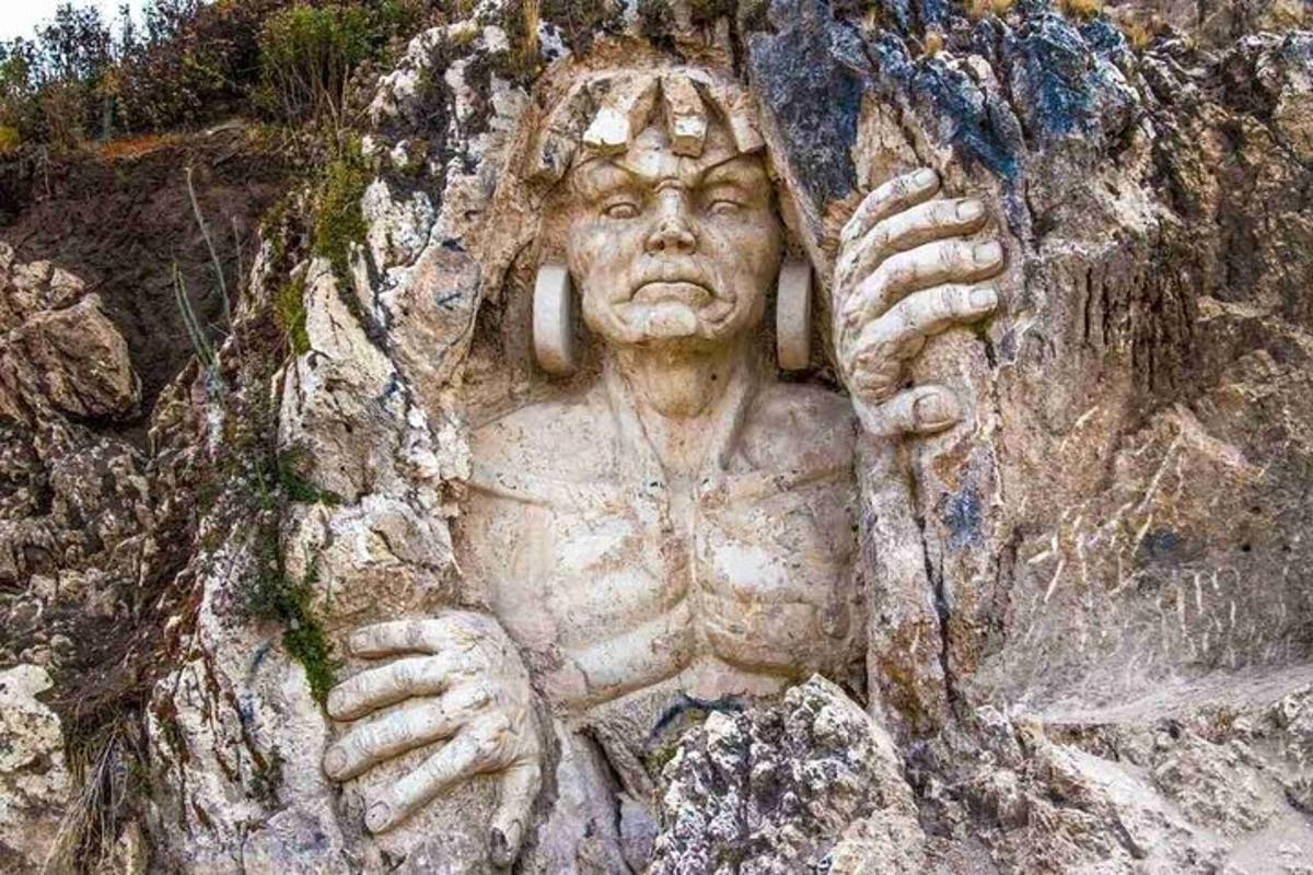 o statuie a unui bărbat pe un perete de stâncă