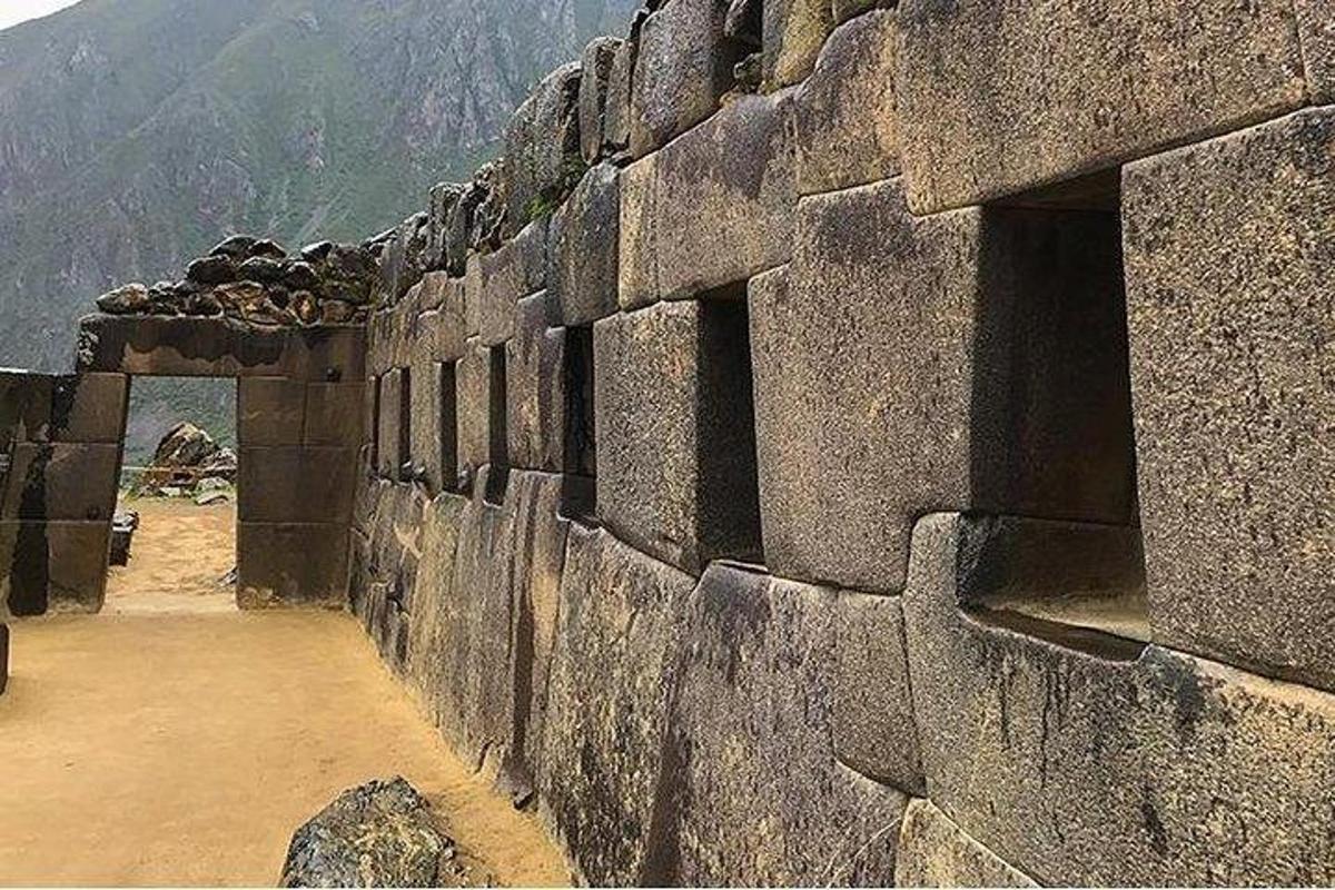 un grande muro di pietra con una montagna sullo sfondo