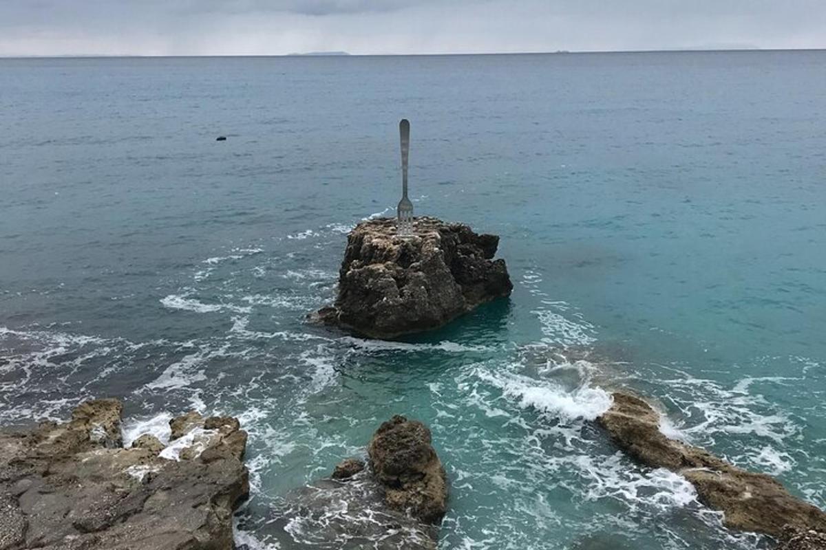 una roccia nell'oceano con un palo sopra