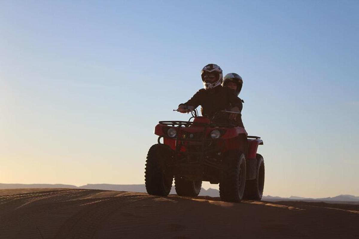 dua orang menunggang basikal quad di padang pasir