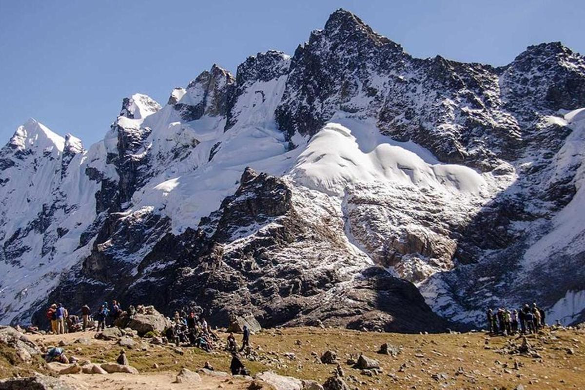Un grupo de personas de pie frente a una montaña cubierta de nieve.