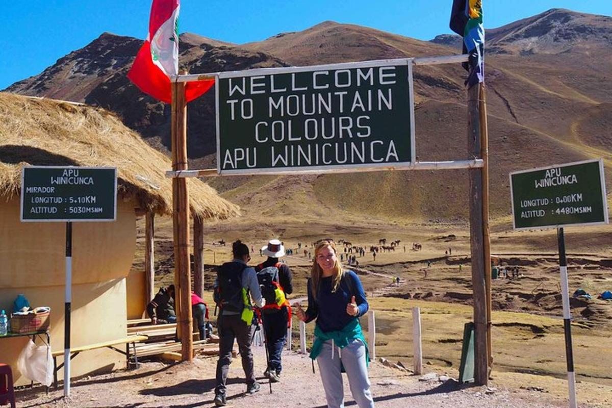 Un grupo de personas de pie bajo un cartel en las montañas.