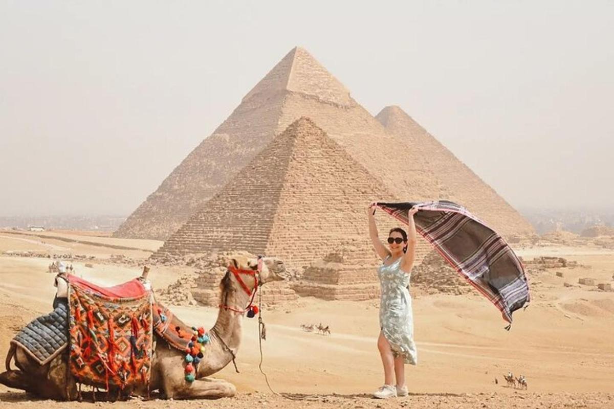 žena stojící vedle velblouda a pyramid