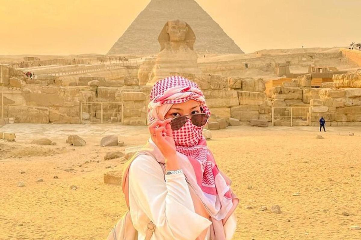 žena mluvící po mobilu před pyramidami